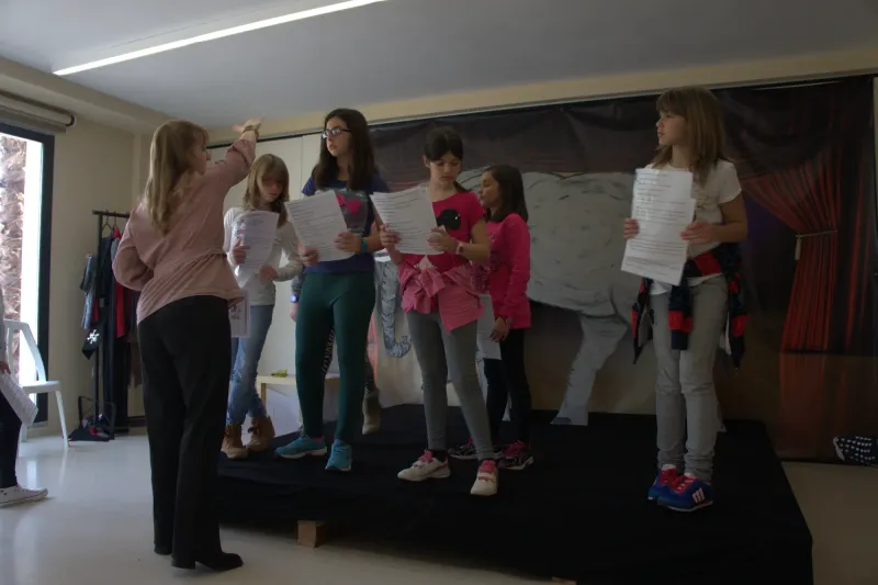 Alumnas ensayan una obra sobre el escenario con el guion en la mano