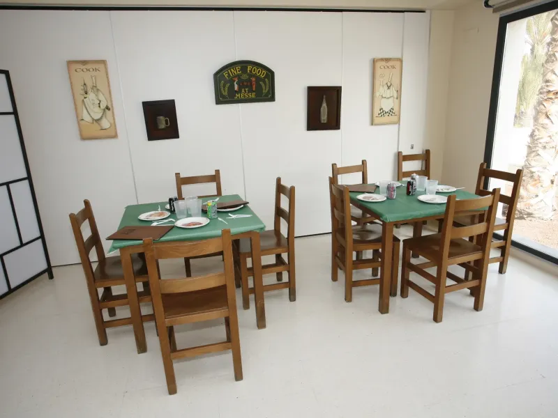 Aula ambientada como restaurante con mesas de madera y manteles verdes
