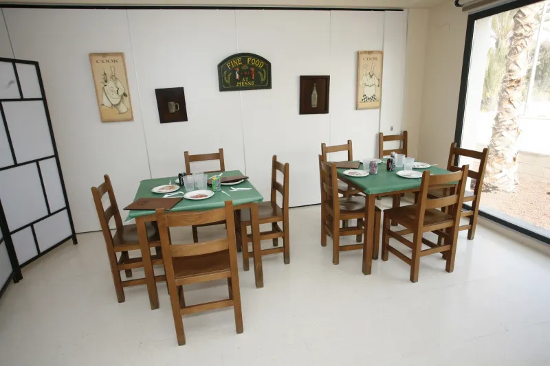 Aula ambientada como restaurante con mesas de madera y manteles verdes