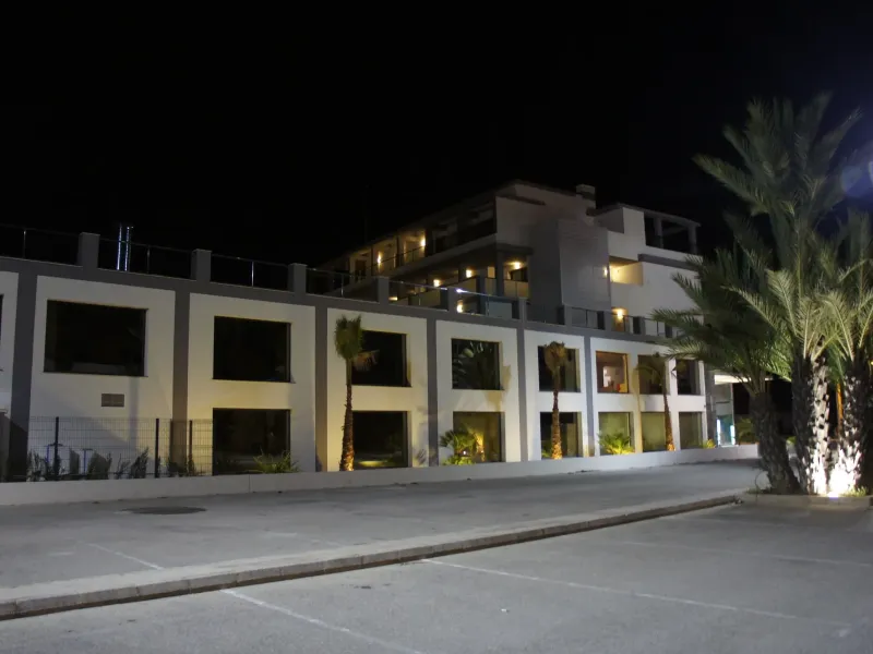 Exterior del hotel y jardín con palmeras iluminados de noche