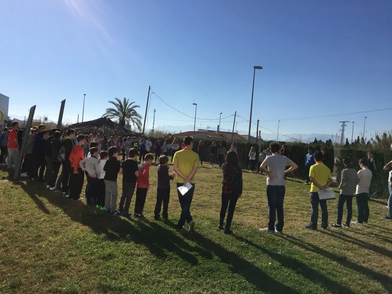 Alumnos forman un gran círculo en el césped durante una actividad al aire libre