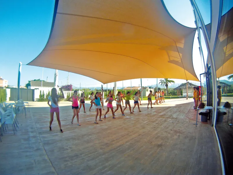 Alumnos bailan en fila bajo una carpa en la terraza del hotel