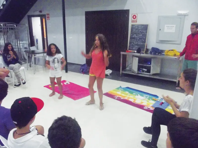 Dos alumnas bailan en una actuación nocturna rodeadas de compañeros