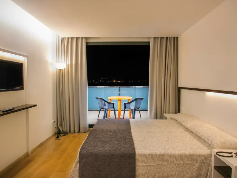 Habitación doble con cama, televisor y terraza con vistas nocturnas